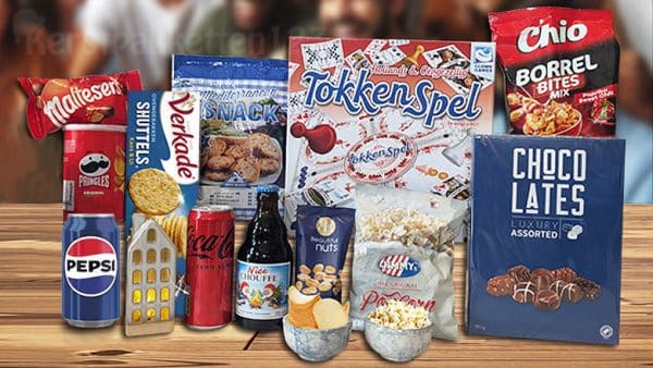 Kerstpakket met tokkenspel, led-huisje, blauwe schaaltjes, chocolade, snacks en frisdrank op een witte ondergrond