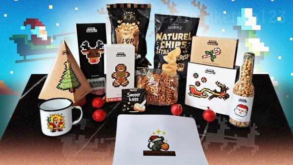 Pixel Perfect kerstpakket met mok, muismat, snacks, chocolade, thee en feestelijke Pixel-art verpakking.