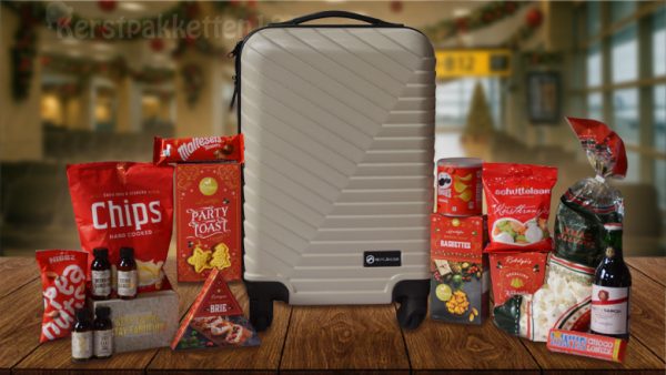 Luxe kerstpakket met taupekleurige trolley, rode kerstverpakking, snacks, chocolade, wijn en travelset op houten tafel
