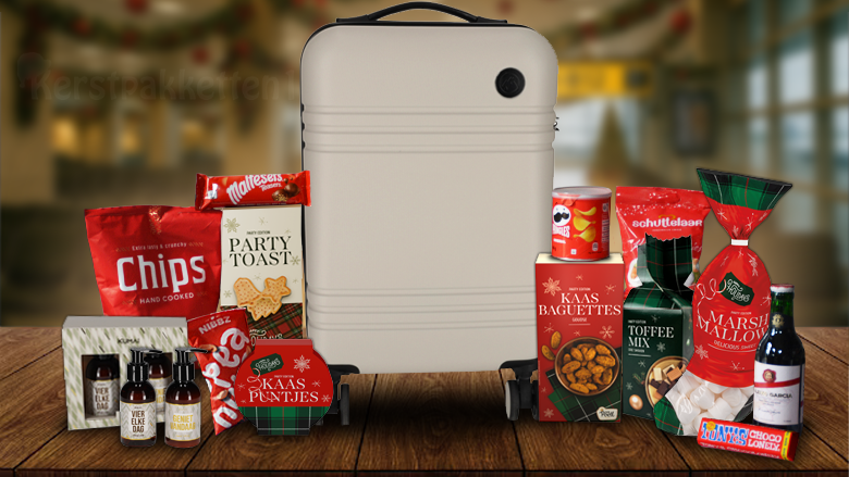Luxe kerstpakket met taupekleurige trolley, rode kerstverpakking, snacks, chocolade, wijn en travelset op houten tafel