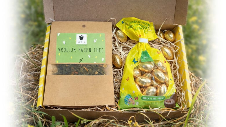 Brievenbus paasgeschenk met vrolijk pasen thee, chocolade paaseitjes en theefilters in gele doos in lentesfeer